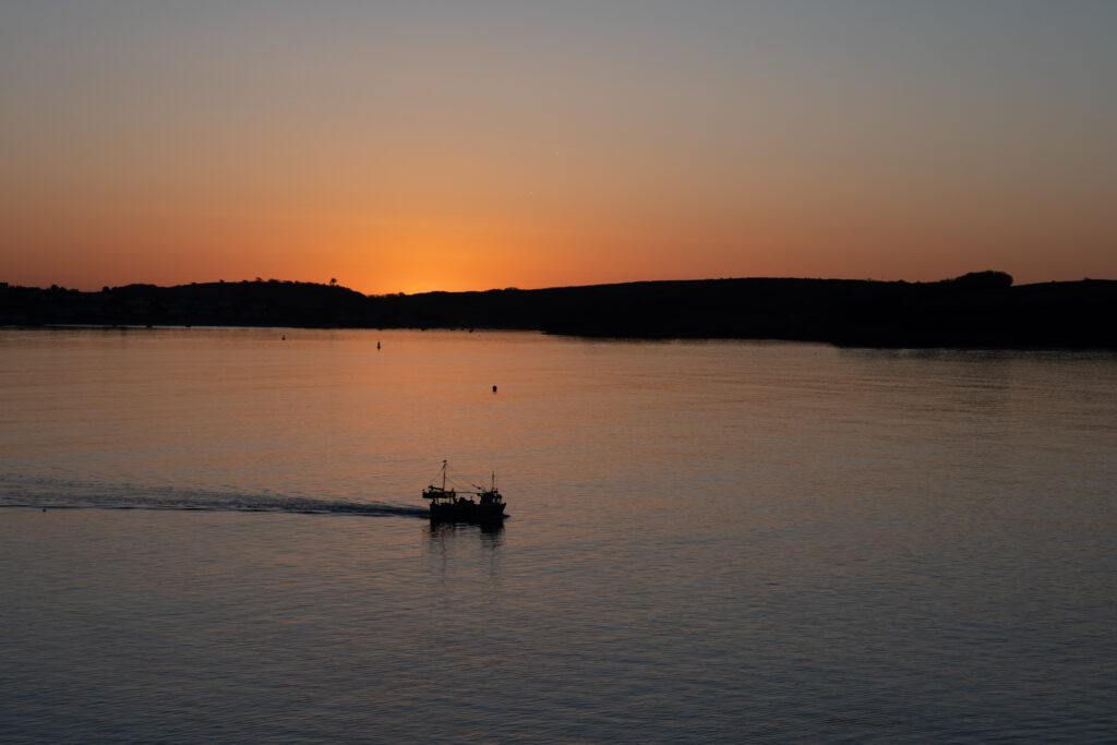 A fishing boat sets out at dawn from Falmouth Harbour